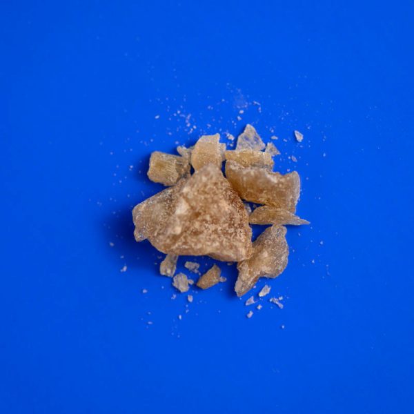 Amber MDMA crystals on blue background